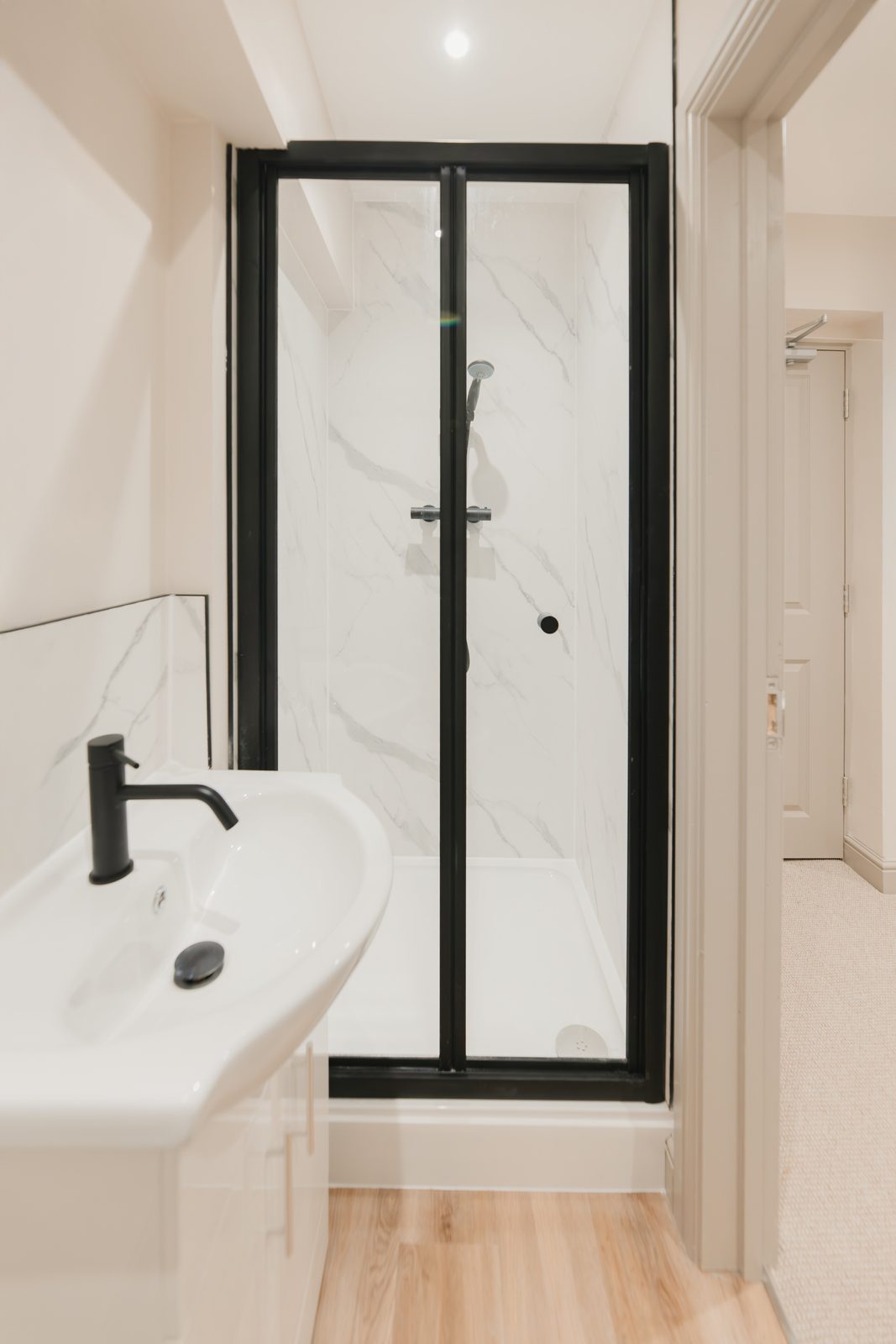 En-suite shower room with black-framed enclosure and marble-effect panelling