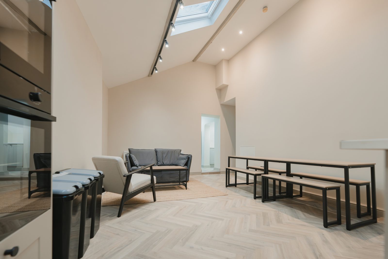 Resident lounge with sofas and communal dining benches under skylights